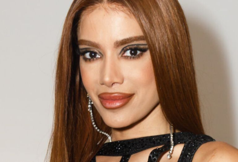 Close-up da cantora Anitta com look preto e maquiagem marcante, em expressão séria e decidida.