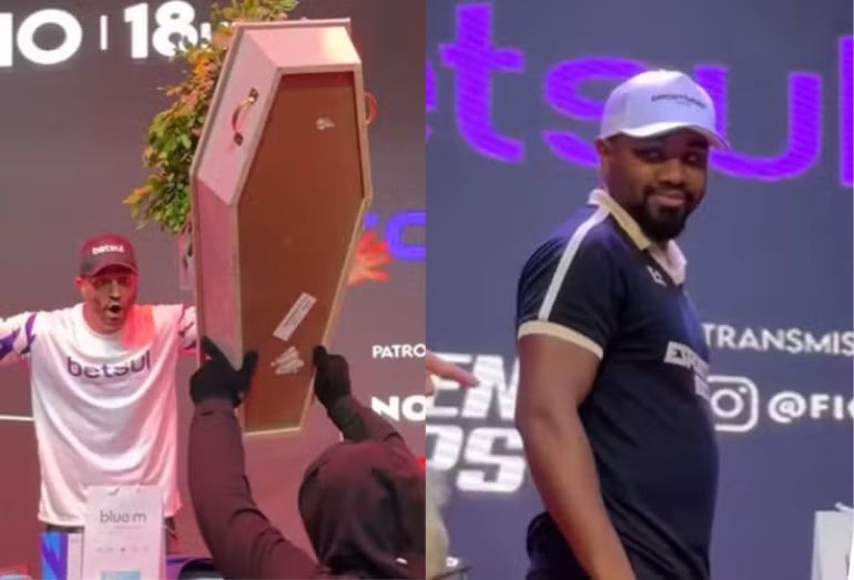 Montagem de duas fotos em uma coletiva de luta. À esquerda, uma figura com luvas pretas ergue um pequeno caixão marrom decorado com flores; atrás, um homem com camisa "betsul" olha com surpresa. À direita, o ex-BBB Davi Brito, com boné e camisa polo preta, sorri e olha para a câmera.