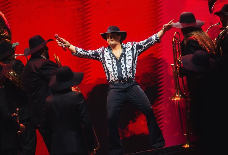 Foto do cantor Natanzinho Lima sorridente no palco, segurando o microfone e apontando para a multidão que lota a gravação do DVD em São Paulo.