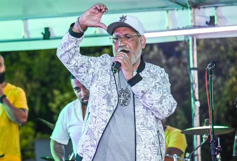Foto de arquivo do cantor de pagode Chrigor Lisboa sorrindo e cantando com um microfone na mão durante um show de samba